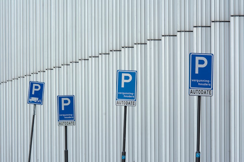 Four blue parking permit signs mounted on metal posts in front of a metallic wall with vertical panels, each displaying a large white 'P' and additional text in Dutch indicating parking permission and auto-dating. The signs are positioned at different heights and angles, with the leftmost sign slightly tilted. The metallic wall behind them features a diagonal line of small, evenly spaced ridges running across its surface, creating a textured background under diffuse natural lighting. The signs relate to parking arrangements in the context of house removals or moving logistics, which is relevant to the service category of Man With a Van Teddington, providing parking permits for relocation vehicles in Teddington.